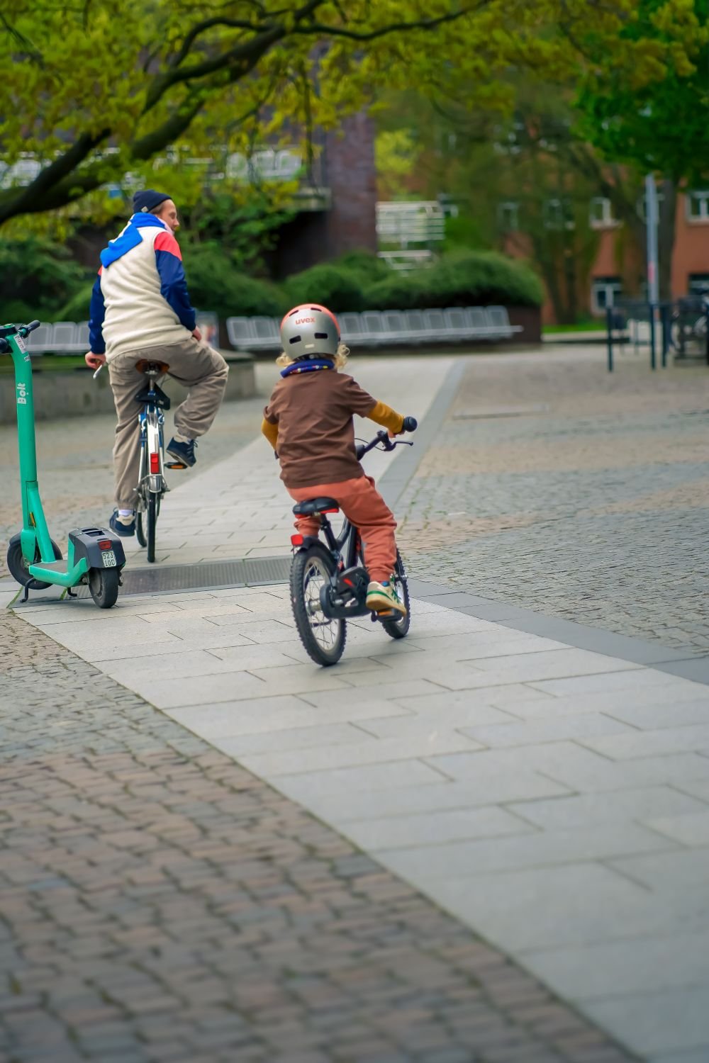 Een kind op een fiets en een volwassene op een fiets in een wijk