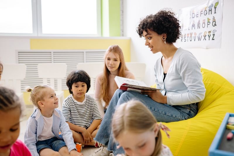 Een begeleider leest voor aan een groepje kinderen