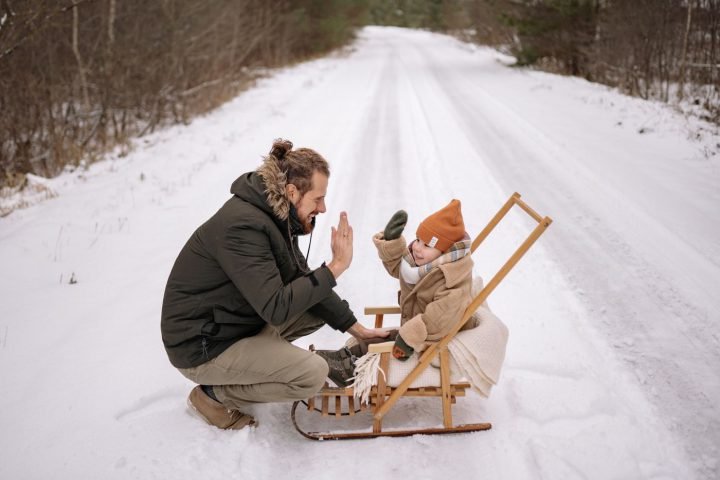 Vader en kind geven elkaar een high five in de sneeuw