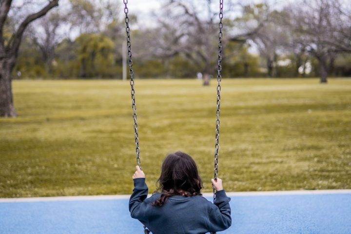 Kind alleen op een schommel in een park